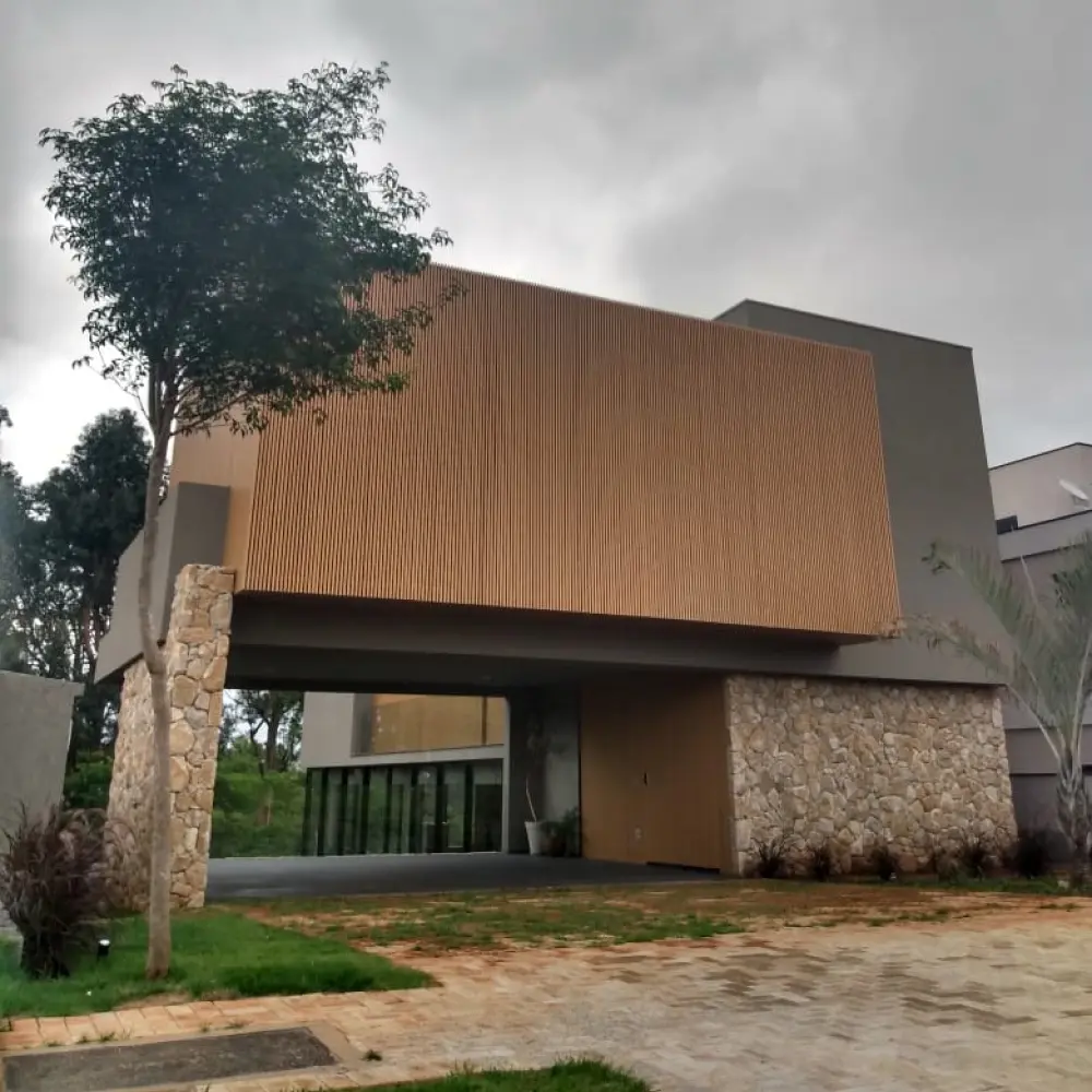 Fachada com volume em ripado de madeira em balanço e base de pedra