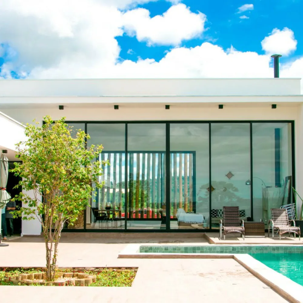 Casa com piscina e grande vão envidraçado em perfil preto, obra da Haus